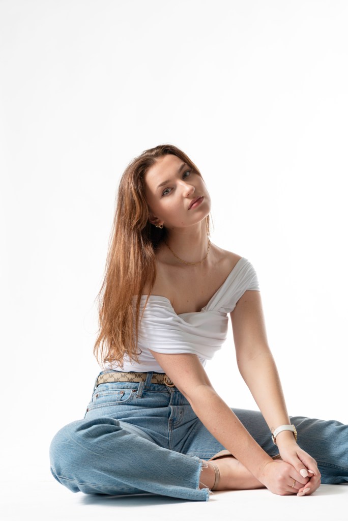 woman sits and holds her crossed leg. studio photography.