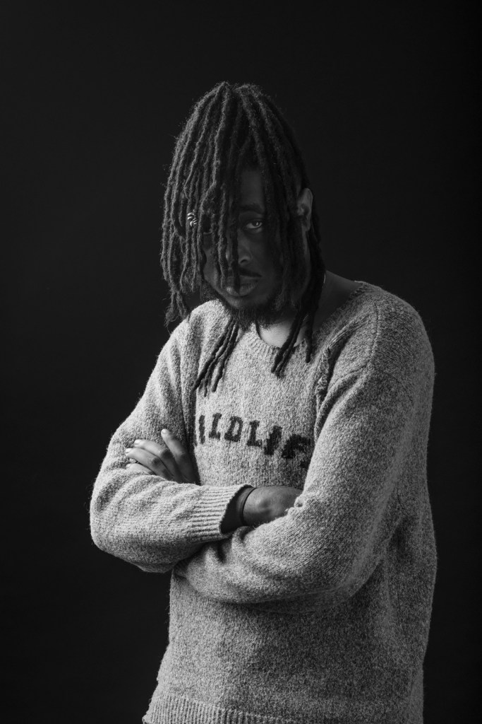 man crosses his arms, his hair covers his face. studio photography.