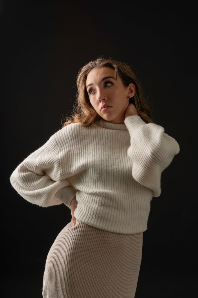 Young woman in sweater and dress; studio photography.