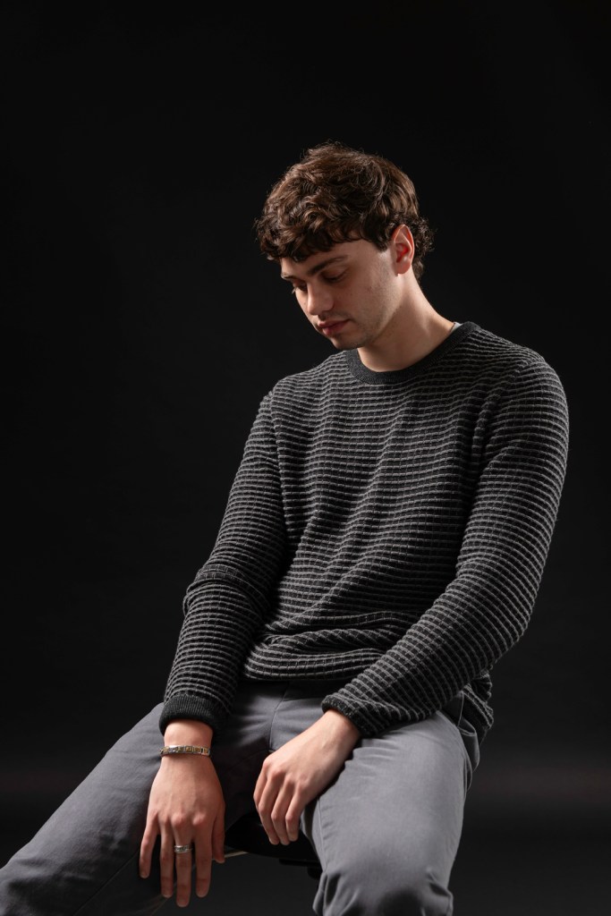 Man sits and looks toward the ground. studio photography.