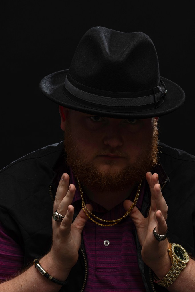 Man with a hat and red beard holds gold chain. studio photography.