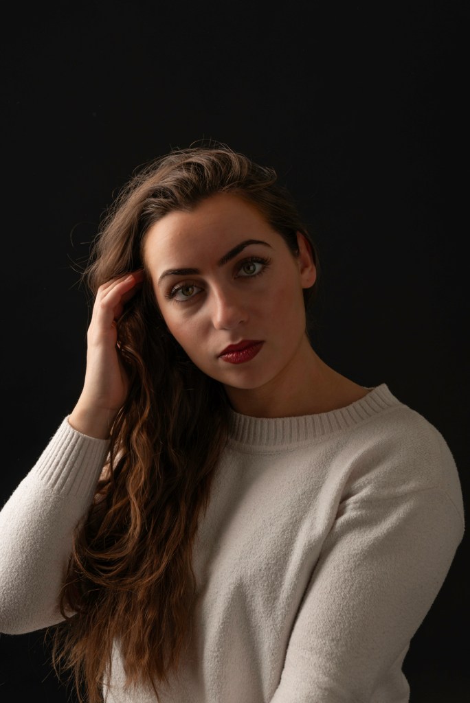 woman tucks her hair behind her ear. studio photography.