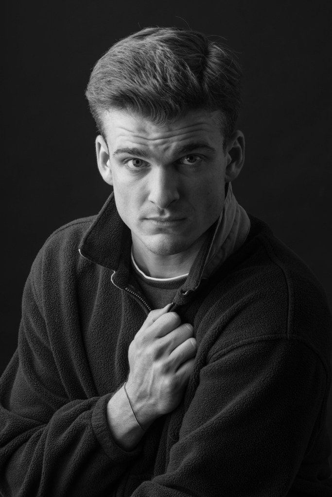 Man holds collar of jacket. studio photography.