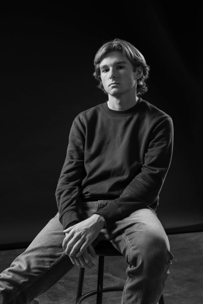 Young man sits with arms crossed. studio photography.