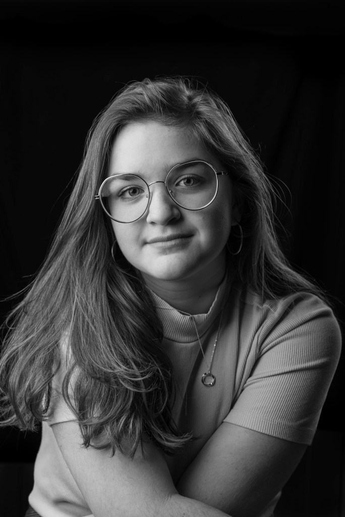 young woman crosses her arms and leans forward. studio photography.