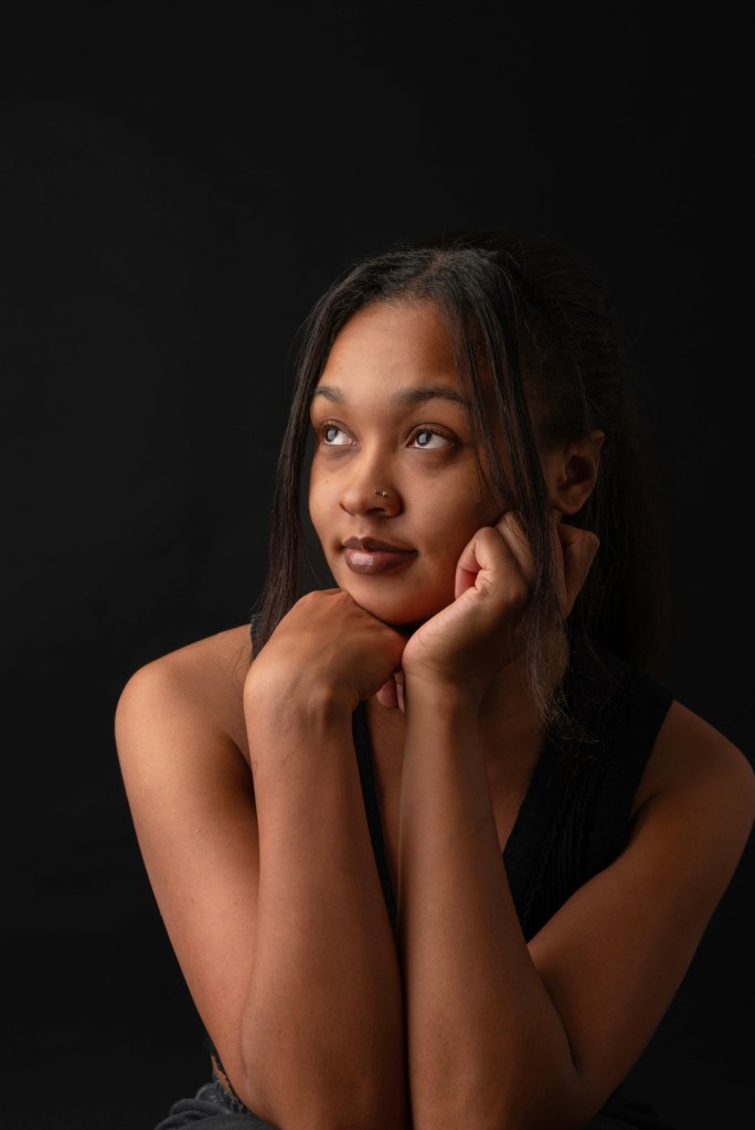 woman rests her head on her hands and looks to the left. studio photography.